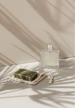 Perfume bottle and soap bar on a sunlit surface